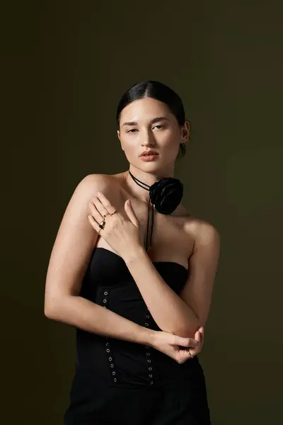 A young woman with brunette hair poses in a black dress with a flower choker necklace. — Stock Photo