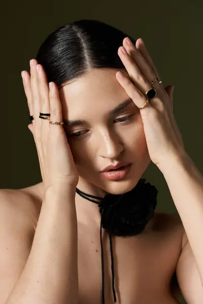 A young woman with dark hair and flawless skin poses with a flower choker necklace against a black background. — Stock Photo