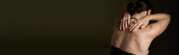 A young woman with brunette hair and rings poses against a black background. — Stock Photo