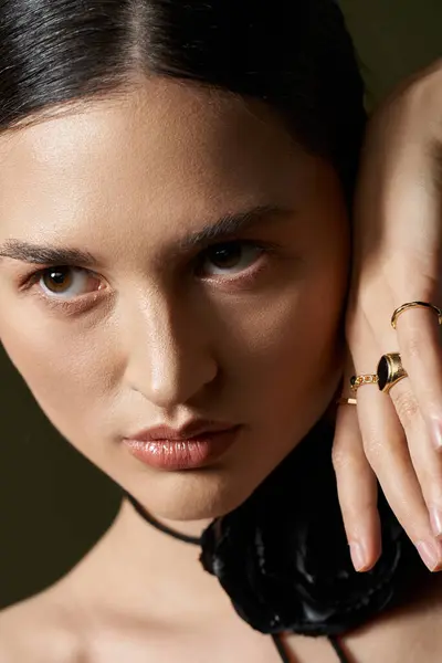 A young woman with long brunette hair, wearing a flower choker necklace, stares intensely at the camera against a black background. — Stock Photo