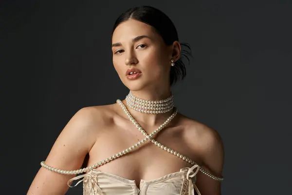 A young woman with dark hair wears a stunning pearl necklace and earrings, her beauty shining against a dark background. — Stock Photo