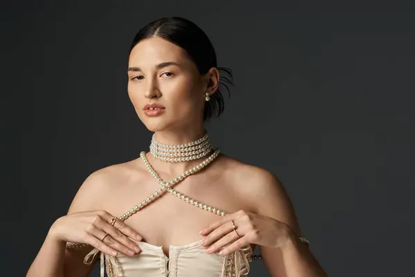 Una giovane donna dai capelli scuri indossa una collana di perle e orecchini sullo sfondo scuro, mostrando eleganza e bellezza senza tempo. — Foto stock
