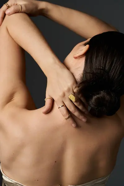 Una joven de cabello oscuro exhibe sus anillos dorados sobre un fondo oscuro. - foto de stock