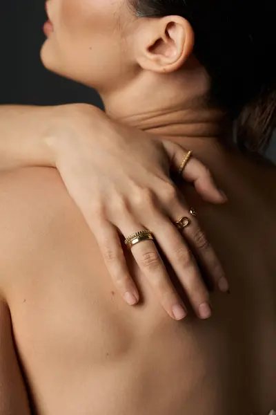 A young woman with dark hair shows off her golden rings against a dark background. — Stock Photo