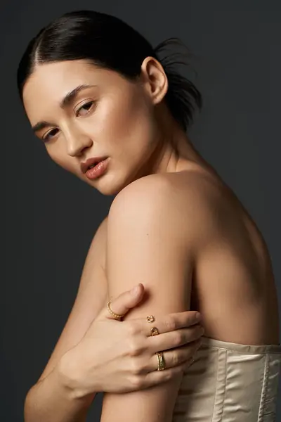 Una joven de cabello oscuro exhibe sus anillos dorados sobre un fondo oscuro, mostrando elegantes joyas y moda. — Stock Photo