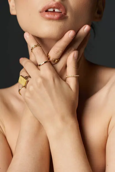 A young woman with dark hair displays her golden rings on her fingers against a dark background. — Stock Photo