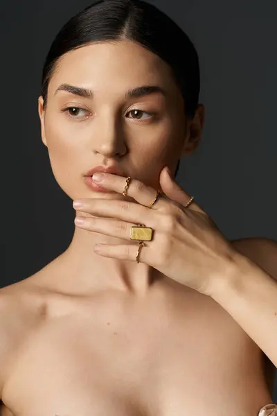 A close-up portrait of a young brunette woman displaying her golden rings on her fingers against a dark background. — Stock Photo