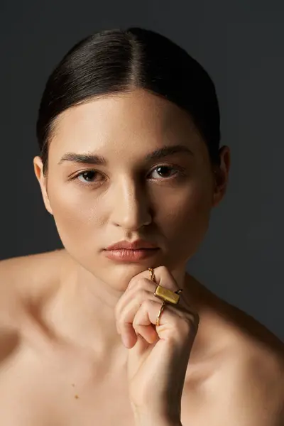Una giovane donna con i capelli scuri mostra i suoi anelli d'oro su uno sfondo scuro. — Foto stock