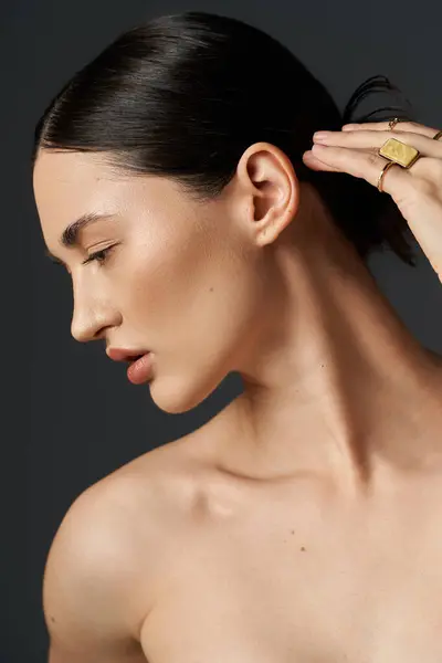 A young woman with dark hair showcases her golden rings against a dark background, highlighting the beauty of simple elegance. — Stock Photo