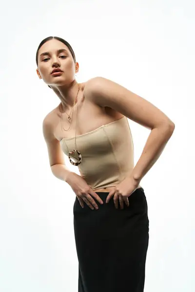 A young brunette woman with a confident expression models beautiful jewelry while wearing a light-colored top and black skirt. — Stock Photo