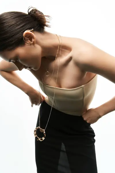 A young woman with long brunette hair shows off her elegant jewelry against a white backdrop. — Stock Photo
