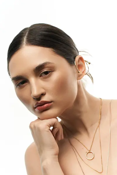 A young woman with brunette hair showcases her exquisite jewelry against a pristine white backdrop, radiating beauty and elegance. — Stock Photo