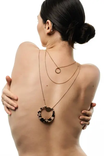 Una giovane donna dai capelli castani mostra una lussuosa collana con un ciondolo grande e unico sullo sfondo bianco. — Foto stock
