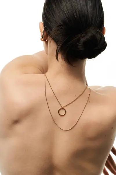A young woman displays her elegant gold necklace on a white backdrop. — Stock Photo