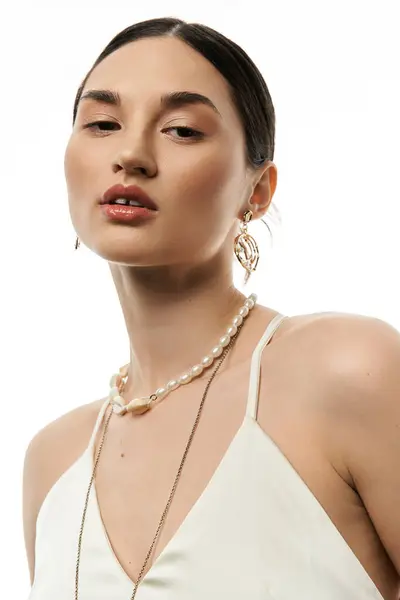 A young brunette woman in a tank top poses against a white backdrop, showcasing her beautiful and luxurious jewelry. — Stock Photo