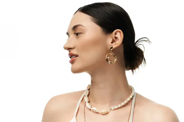 A young brunette woman with beautiful features showcases luxurious jewelry against a white backdrop. — Stock Photo