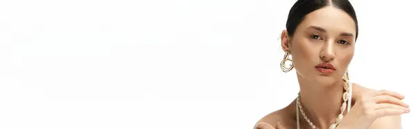 A young brunette woman with flawless makeup and a confident expression displays her beautiful jewelry on a white background. — Stock Photo