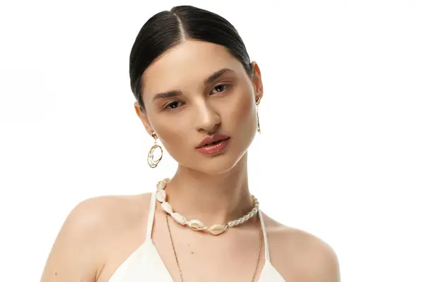 A young woman with dark hair showcases her beautiful jewelry, featuring a necklace and earrings made from delicate seashells. — Stock Photo