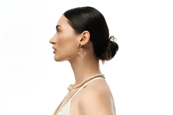 A young woman with dark hair showcases her beautiful, luxurious jewelry against a clean white background. — Stock Photo