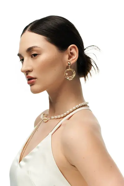 A young woman with dark hair is shown wearing gold earrings and a pearl necklace, showcasing her beautiful and luxurious jewelry. — Stock Photo