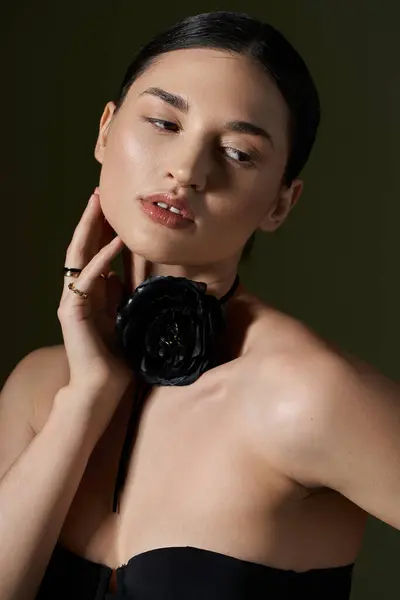 A young woman with brunette hair poses against a black background, wearing a black rose choker. — Stock Photo