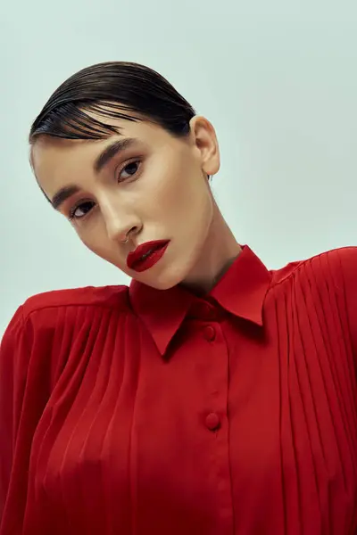 A young woman with short hair poses in a red blouse, showcasing a bold and confident style. — Stock Photo
