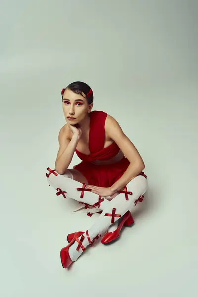 Una giovane donna con i capelli corti posa in un crop top rosso e mini gonna, ornata con fiocchi rossi. — Foto stock