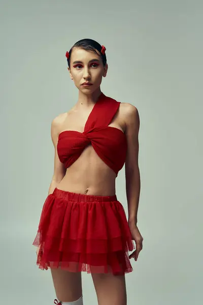 A young woman with short hair poses in a red outfit in a studio setting. — Stock Photo