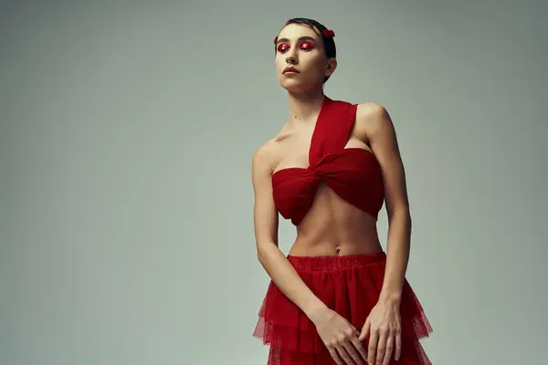 A young woman in a red attire poses in a studio setting. — Stock Photo