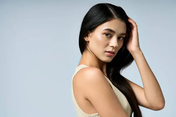Donna con i capelli neri posa sullo sfondo blu, spettatore accattivante. — Foto stock