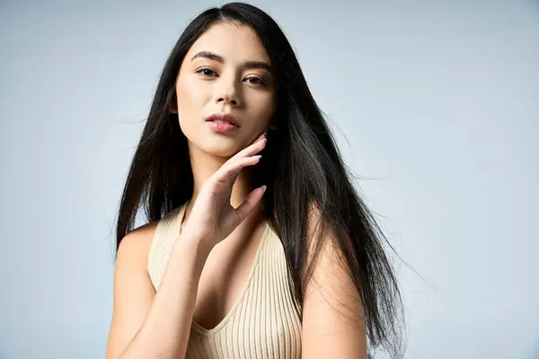 A young woman with long black hair poses confidently, wearing a stylish beige top. — Stock Photo