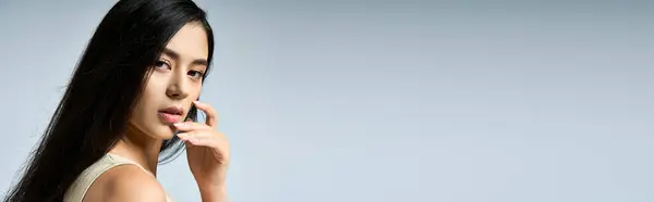 A young woman in fashionable attire poses with a serene expression against a pale backdrop. — Stock Photo