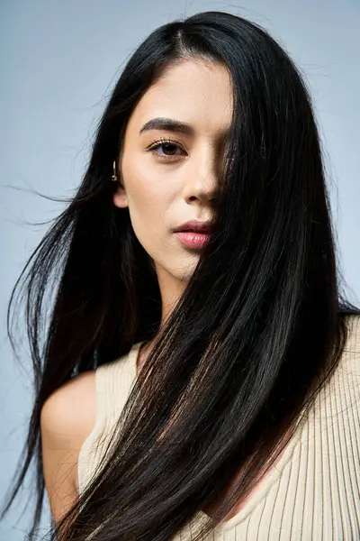A young woman with long black hair poses with a serious expression. — Stock Photo