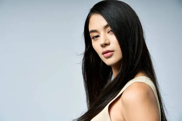 A young woman with long black hair poses against a light background. — Stock Photo