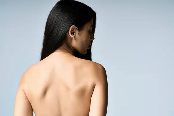 A young woman poses with her back to the camera, her long black hair cascading down her shoulders. — Stock Photo