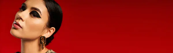 Eine junge Frau mit dunklen Haaren und fettem Make-up posiert vor rotem Hintergrund. — Stockfoto