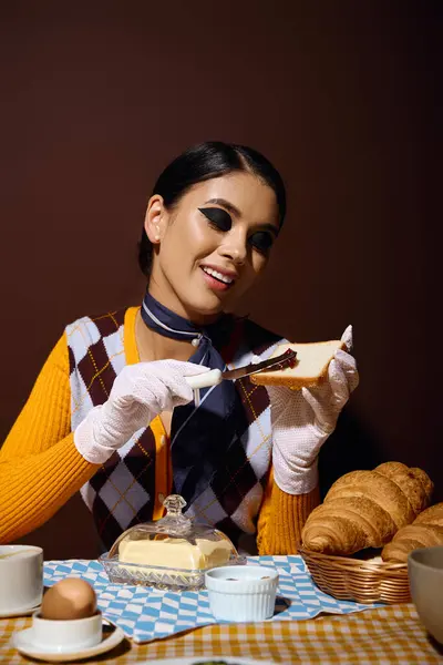 Uma jovem mulher com cabelo escuro e uma roupa elegante desfruta de um café da manhã de torradas e croissants. — Fotografia de Stock