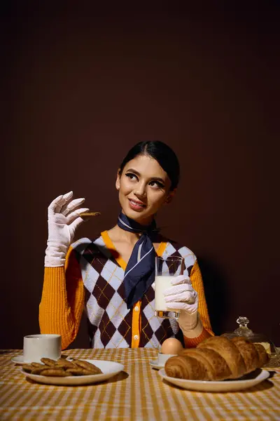 Eine junge Frau im schicken Pullover genießt ein morgendliches Frühstück mit Croissants und Milch. — Stockfoto