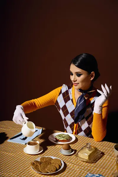 Una mujer joven en un traje de moda vierte crema en su café en una mesa de desayuno. - foto de stock