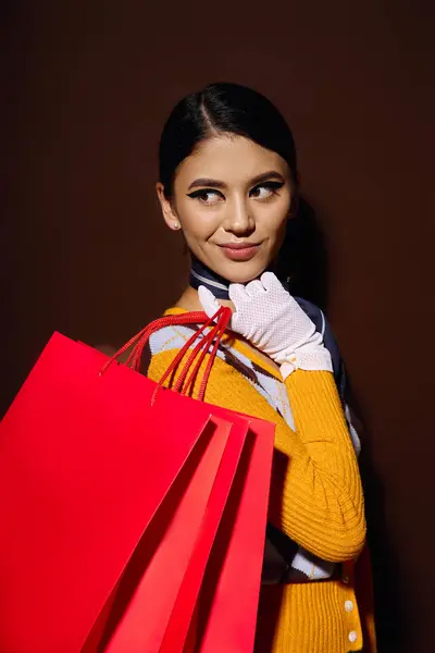 Uma jovem mulher em uma camisola amarela e luvas brancas posa com sacos de compras. — Fotografia de Stock