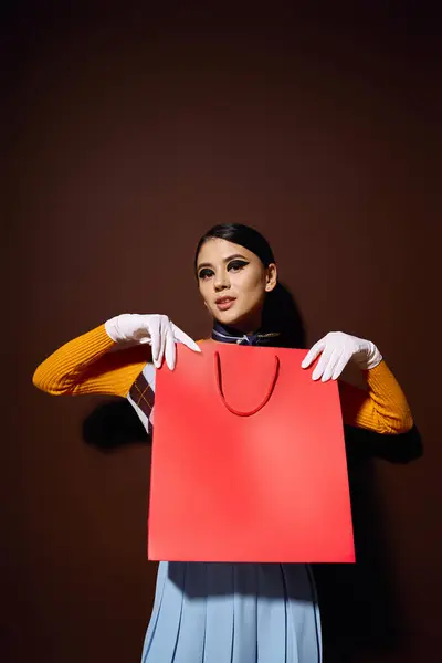 Uma jovem mulher em uma roupa elegante detém um grande saco de compras vermelho. — Fotografia de Stock
