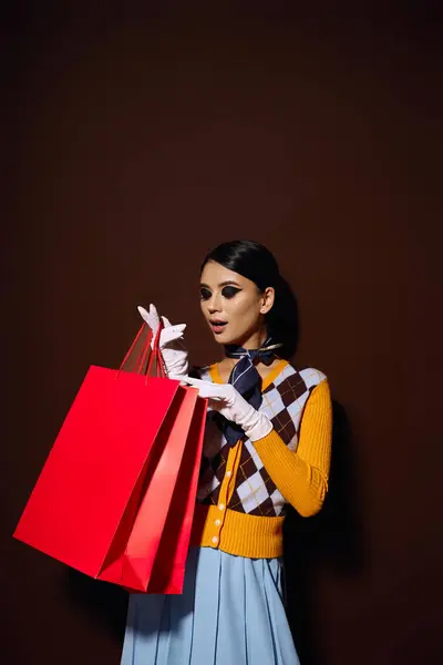 Uma jovem na moda em uma camisola amarela olha entusiasmadamente para sacos de compras em suas mãos. — Fotografia de Stock