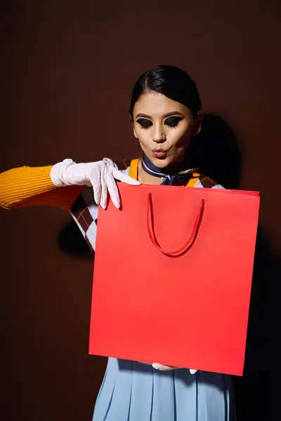 Uma jovem mulher em uma roupa elegante detém um saco de compras vermelho, olhando animado sobre o conteúdo. — Fotografia de Stock