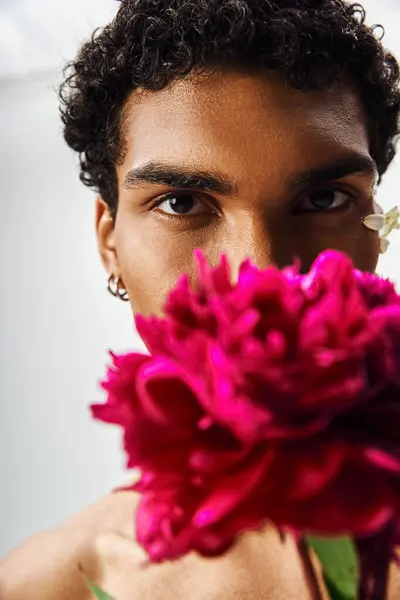 A close-up portrait of a young, muscular Black man with a flower covering his face, showcasing beauty and diversity. — Stock Photo