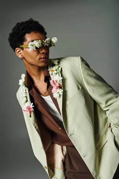A young African American man poses in a stylish blazer, adorned with delicate flowers, creating a unique and striking portrait. — Stock Photo