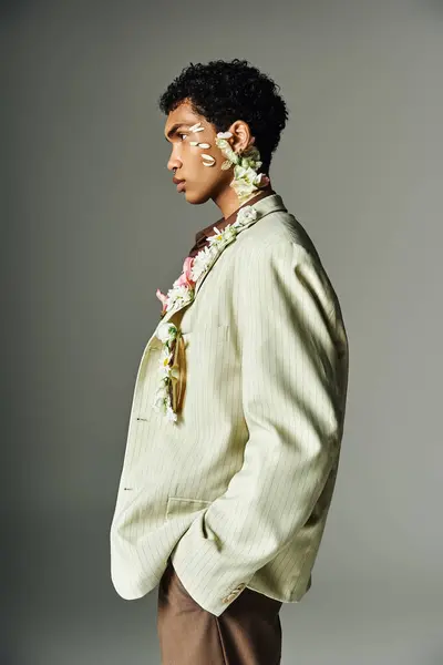 Ein junger afroamerikanischer Mann posiert in einem stylischen Blazer mit Blumen und präsentiert Schönheit und Vielfalt in der Mode. — Stockfoto