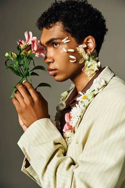 Um jovem afro-americano posa em um blazer elegante com flores adornando seu rosto e pescoço. — Fotografia de Stock