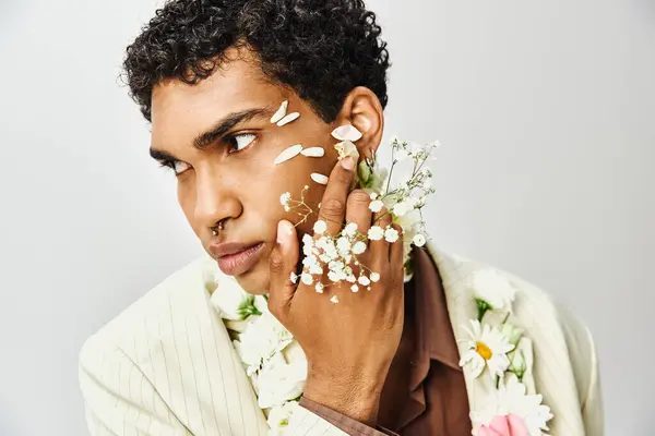 A young African American man poses with flowers on his face and neck, showcasing beauty and diversity. — Stock Photo