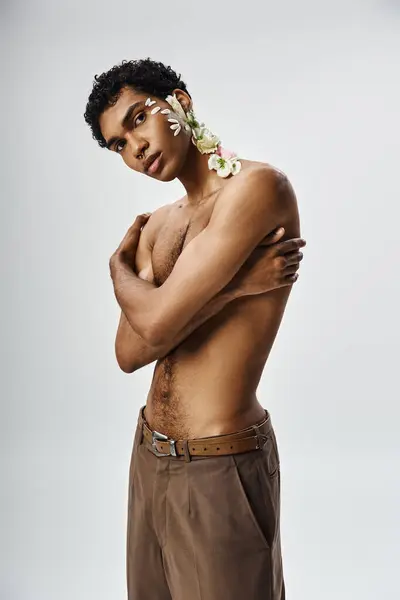 A young, muscular African American man with flowers on his body and face poses against a grey backdrop. — Stock Photo