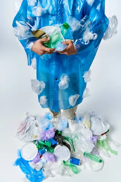 A man stands on a pile of plastic, wearing a plastic coat decorated with plastic. — Stock Photo